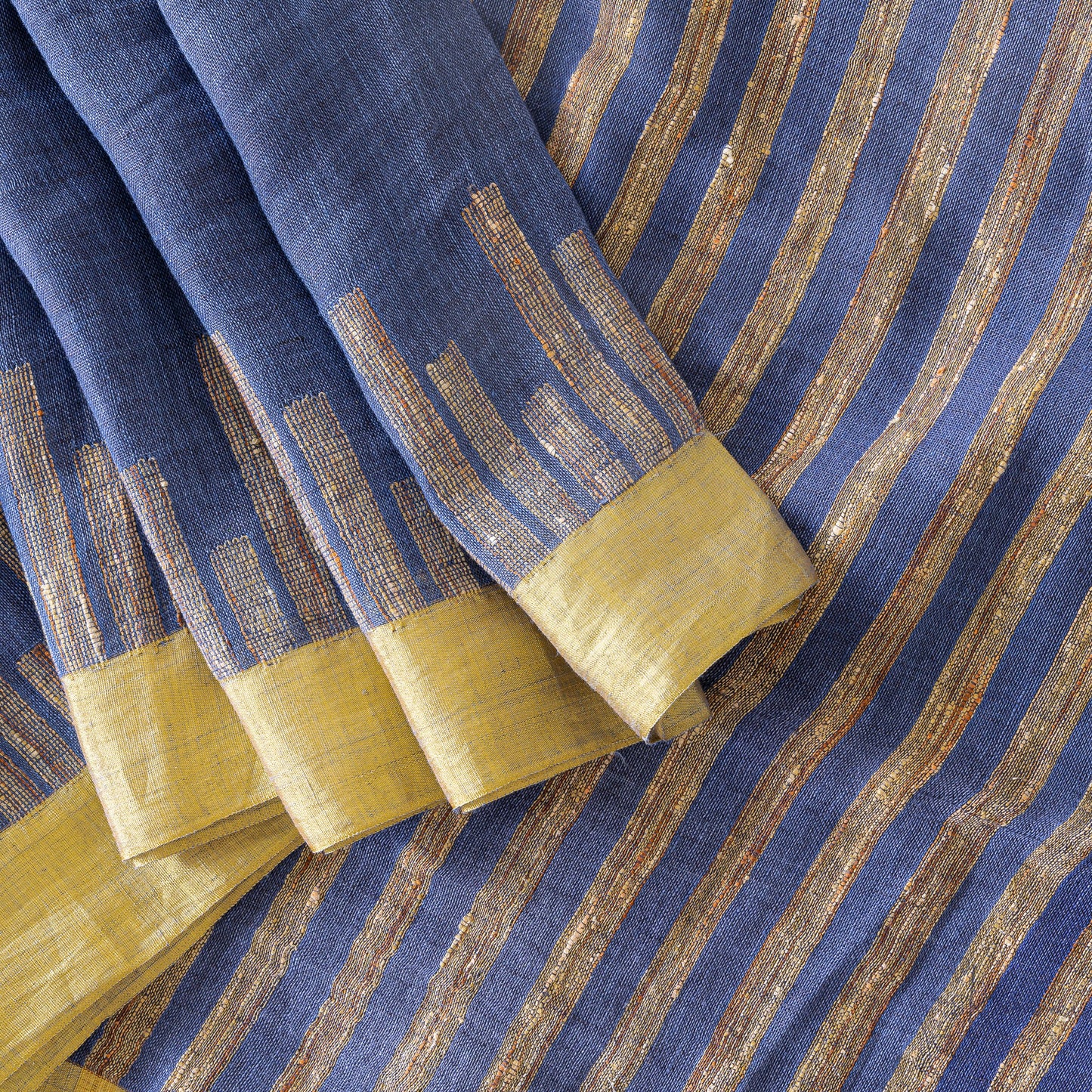 Top view of dark blue linen saree with gold zari work along the border and pallu of the saree.