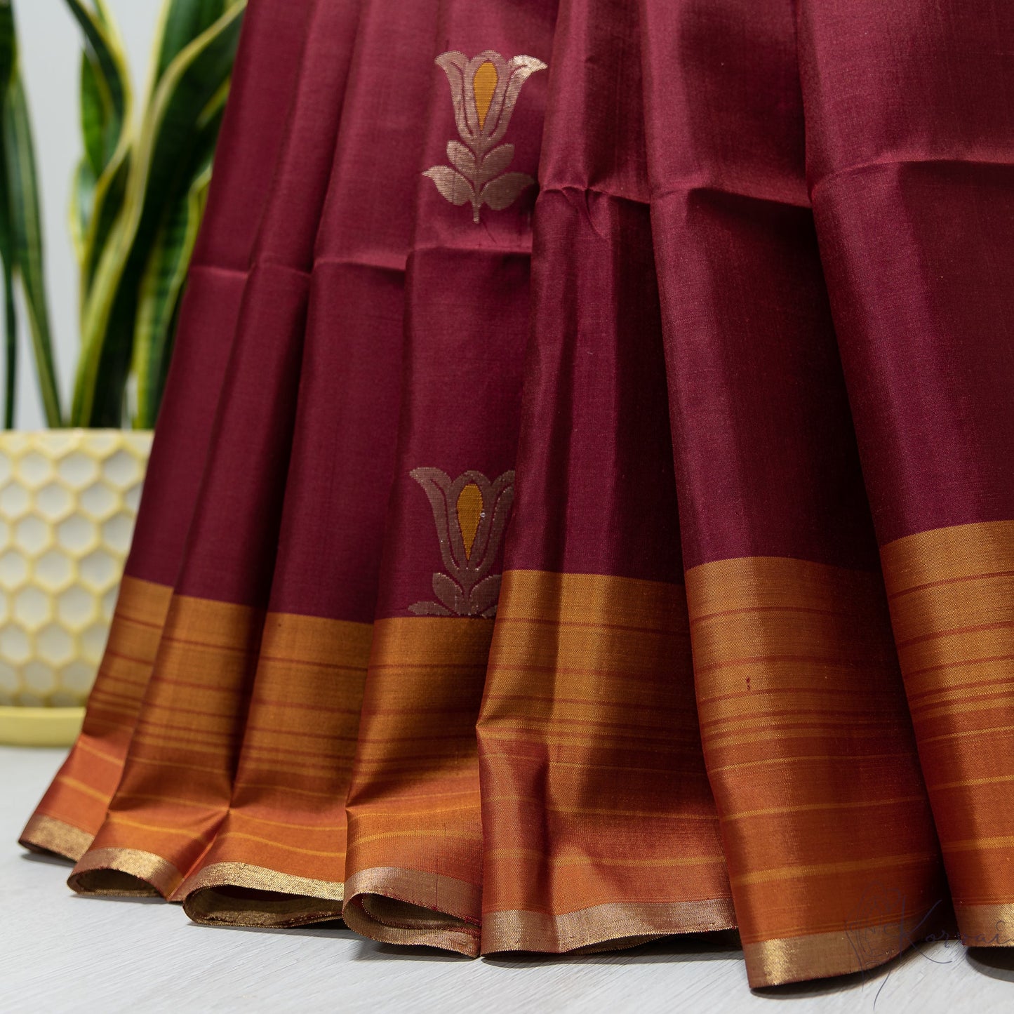 Pleated view of maroon soft silk saree with mustard border.