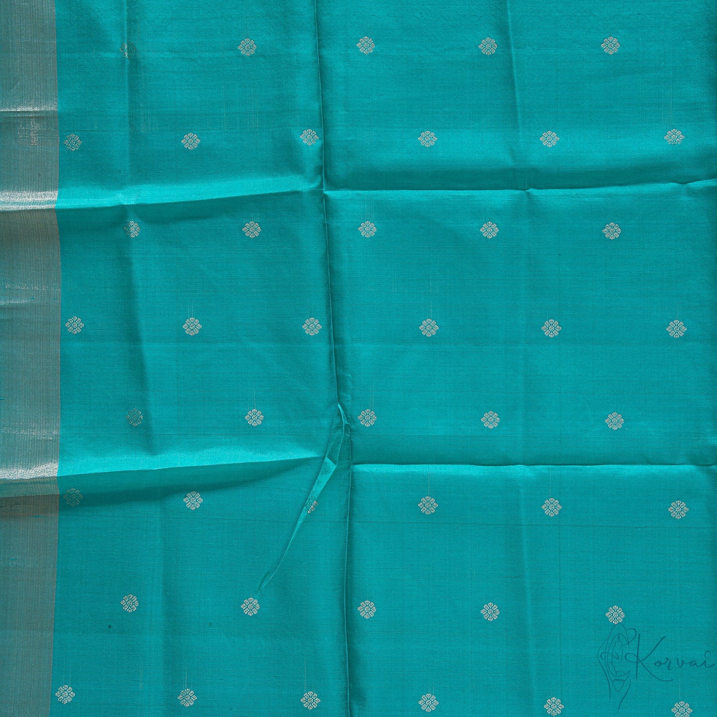Closer view of teal blouse fabric with tiny flower motifs.
