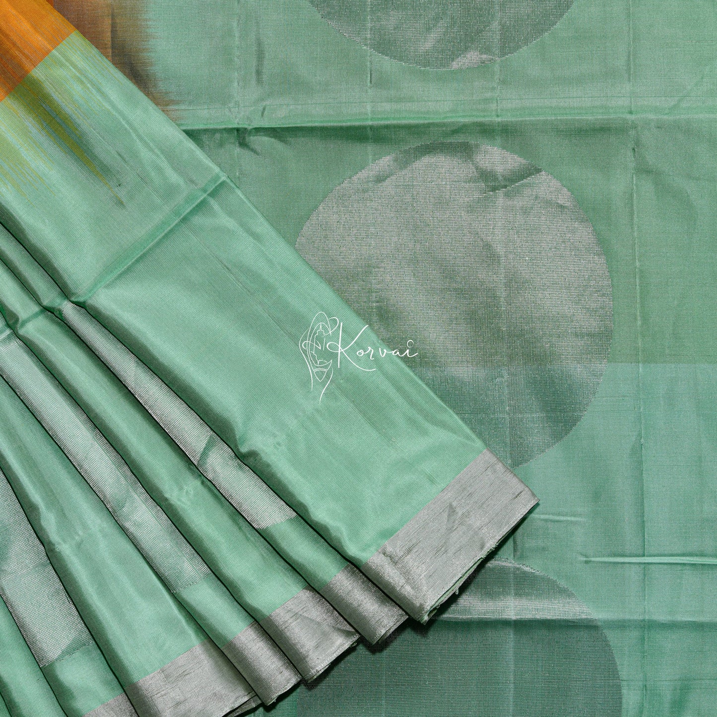 Amber coloured soft silk saree with pastel green pallu and border.