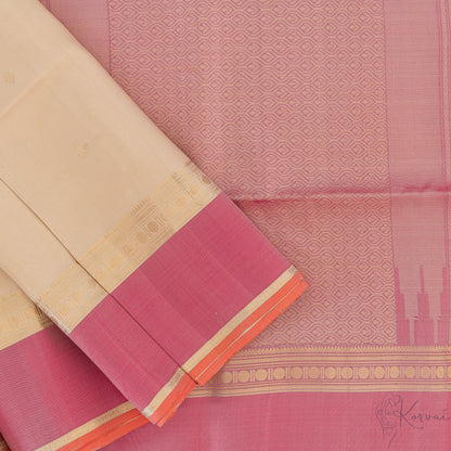 Top view of cream Kanjivaram soft silk saree with pink pallu that has intricate gold zari designs.