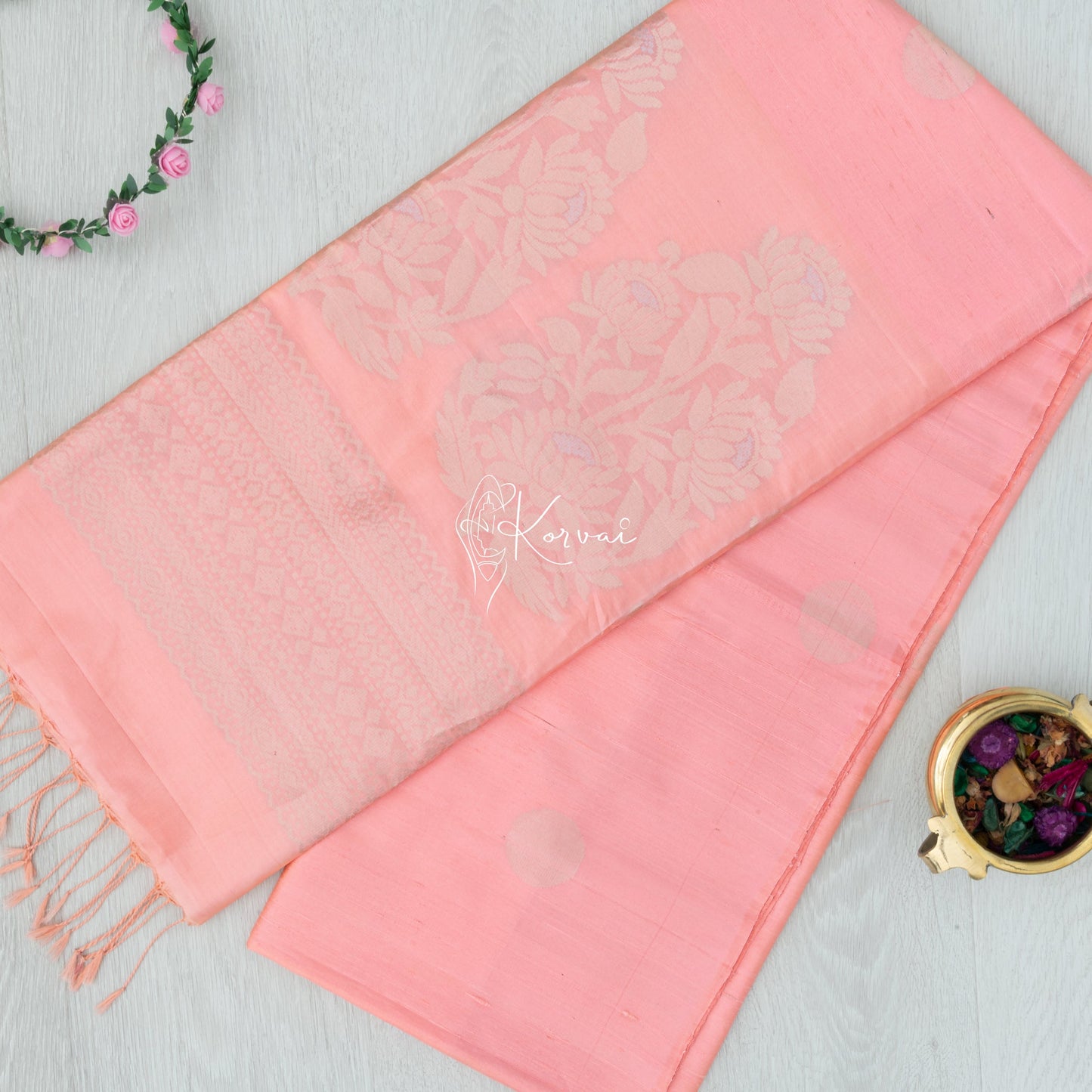 Top view of pinkish peach Kanjivaram raw silk saree with sunflower motifs in gold zari on the pallu.