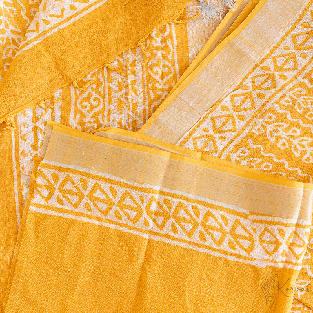 Top view of yellow cotton saree and blouse fabric with white block prints all over.