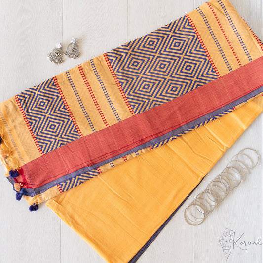 Picture showing a sunset yellow coloured kadhi cotton saree folded in half with pallu facing up. The pallu has dark blue diamond shaped motifs.