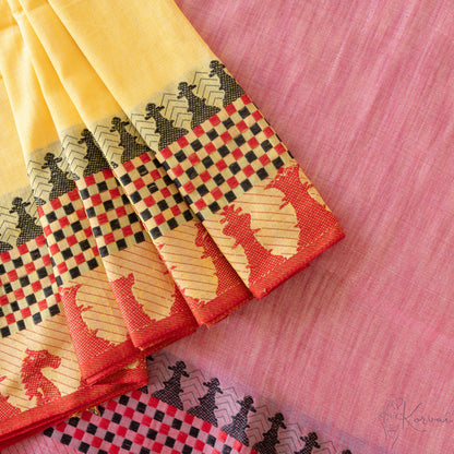 Top view of yellow kadhi cotton saree showing the pink pallu and some pleats.