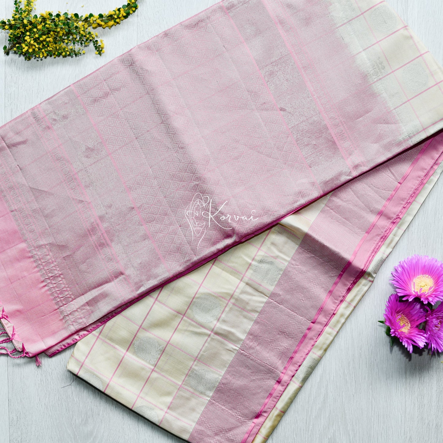 Top view of cream soft silk saree with pink checks and laddu kamalam motifs in silver.