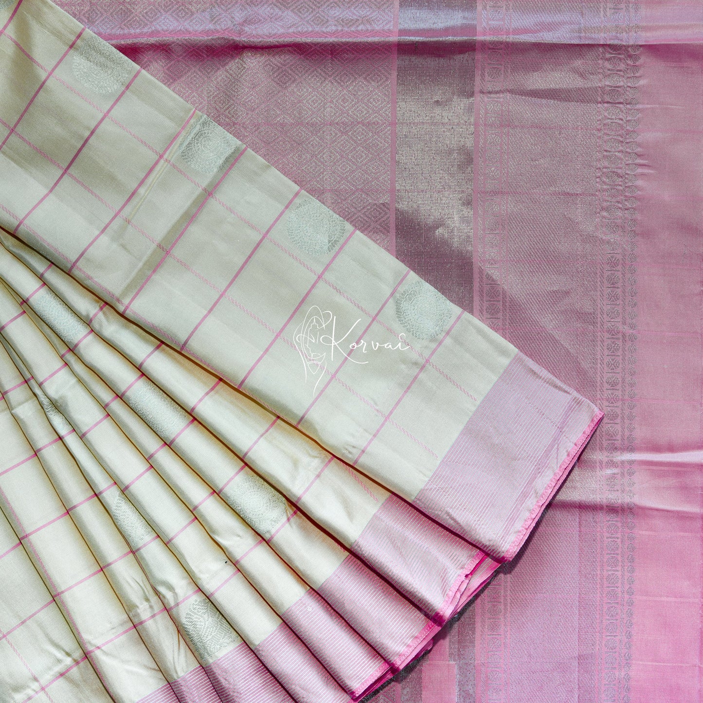 Cream soft silk saree with pink checks and laddu kamalam motifs in the body and pink pallu.